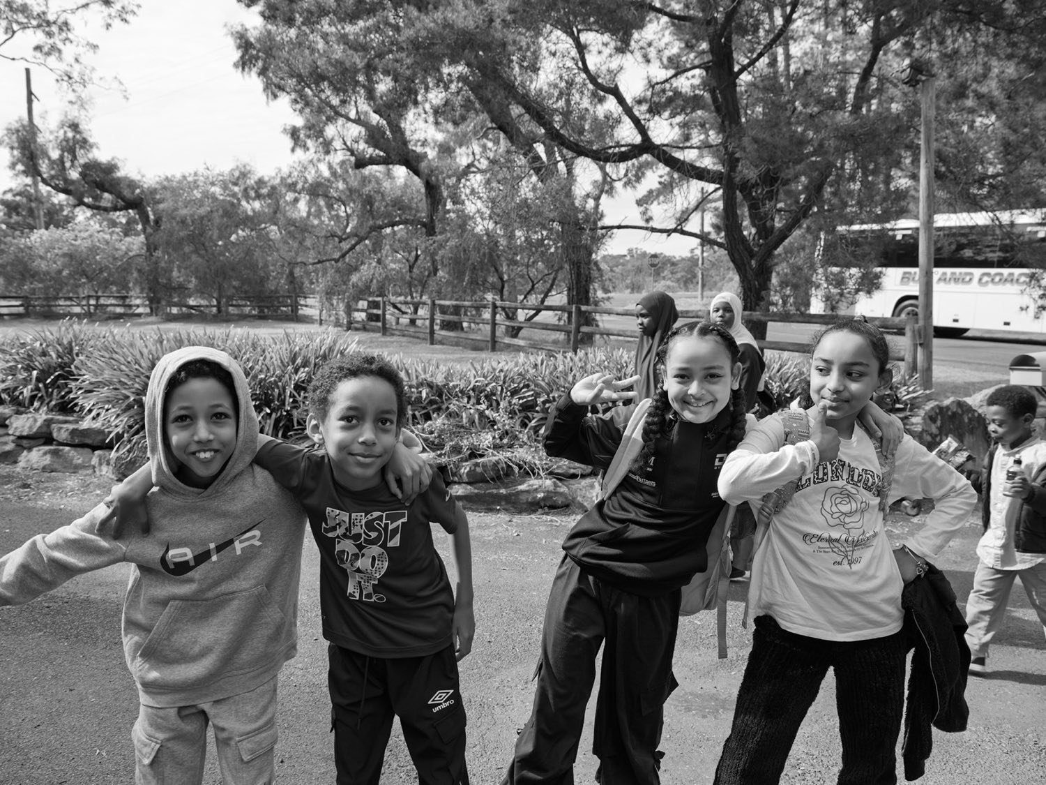 Four children with their arms around each other, laughing, outdoors