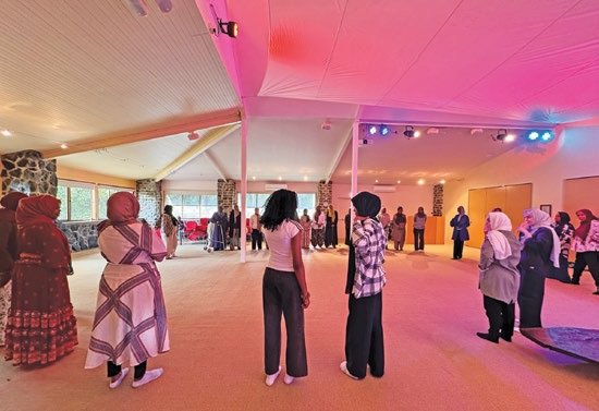 Women standing in a circle in a hall, part-way through a musical game