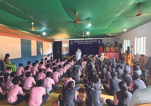 Students seated for an assembly hall talk, lit in green