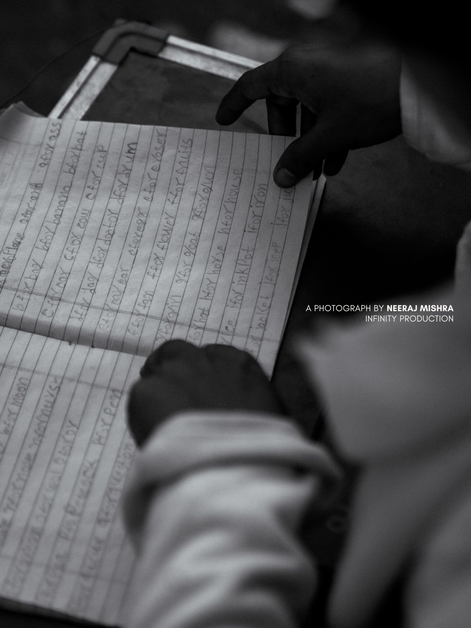 Smriti's hand guiding a child through a handwriting exercise