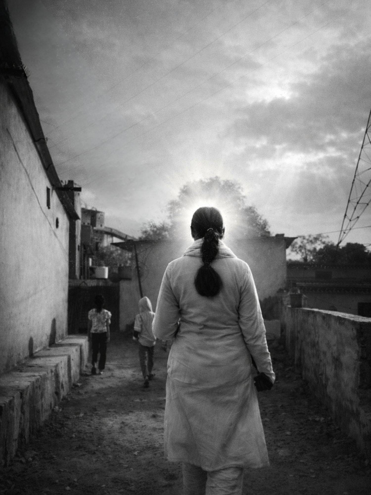 Smriti Budhia walking down a village lane at sunrise, children ahead of her